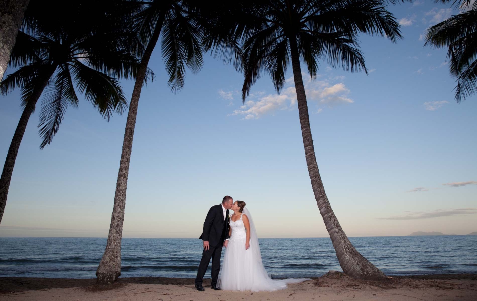 A bride amd groom placed between two palm trees at Palm Cove created by Palm Cove Wedding Photography by Nathan Kelly one of cairns best wedding photographers